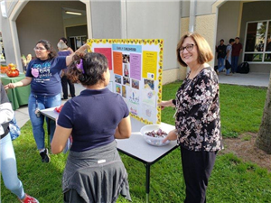 FCCLA Advisor standing at a table giving away candy 